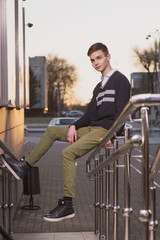 Lifestyle photo of a young brown-haired man on the street in the rays of the setting sun