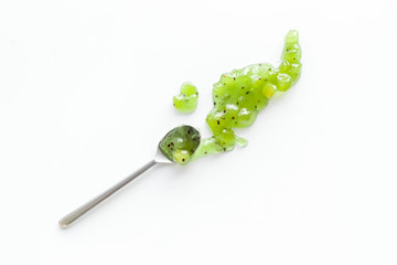 Fruit jam. Green dessert smashed by spoon on white desk