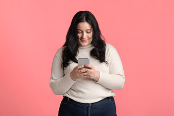 Plus size woman holding smartphone in hands, texting or reading message
