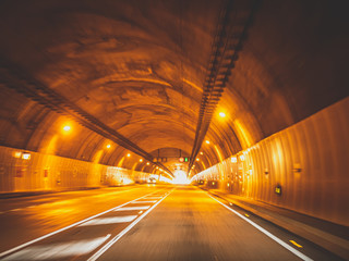 Toned blurred image of cars driving fast in long tunnel under mountain