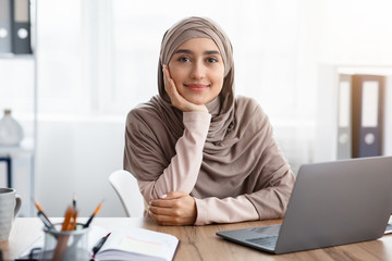 Portrait of muslim female entrepreneur sitting at workplace in modern office