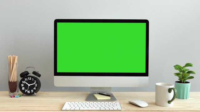 Computer desktop with mock-up green screen white background  in office and ฺblack clock , Zoom shoulder view.