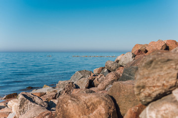 Fototapeta na wymiar Big stones on the seashore. Blue sky merges with the sea