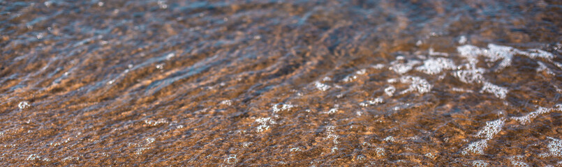 view of the surface of the sea with water and sand reflections. Abstract natural background texture. Horizontal close-up shot.