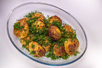Meat cutlets with greens on a transparent dish on a light background