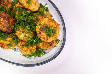 Meat cutlets with greens on a transparent dish on a light background