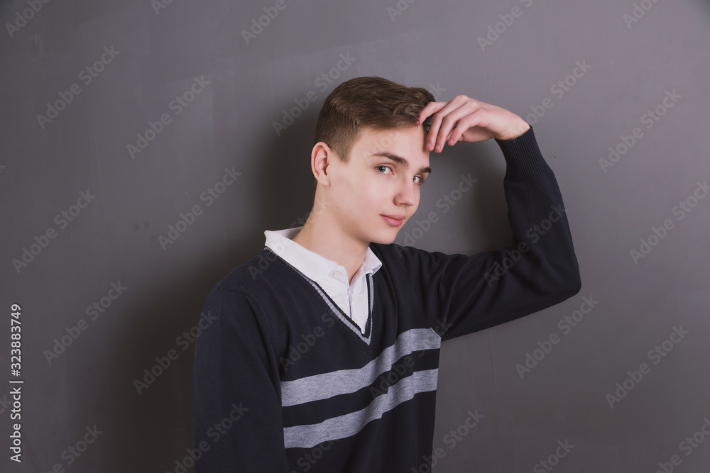 Wall mural Lifestyle photo of a young brown-haired man on a light background, a beautiful young guy in a shirt and sweater