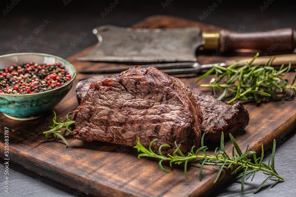 Wall mural two beef rump steaks with herbs tomatoes salt and spices on butcher board