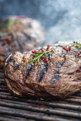 Juicy beef rib eye steaks on the grill with rosemary salt and spices