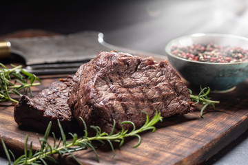 Two beef rump steaks with herbs tomatoes salt and spices on butcher board