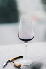 a glass of red wine and a corkscrew on the table