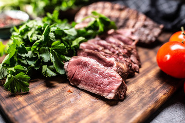 Slices of juicy grilled beef steak on a butcher plate