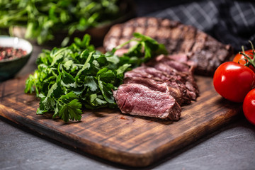 Slices of juicy grilled beef steak on a butcher plate