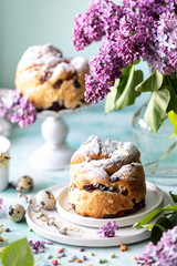 Traditional cupcake Easter cake kraffin with raisins and icing sugar on the table. Easter cakes, candles and a bouquet of lilac flowers.