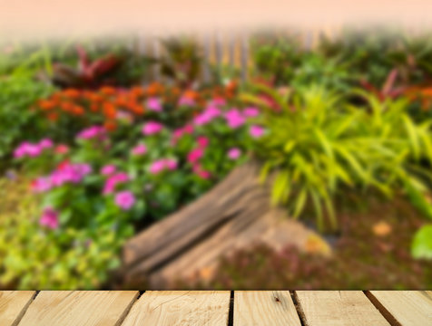 Empty table top for product display montage. Colorful garden blurred for background.