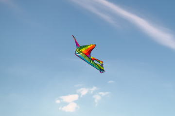Naklejka na ściany i meble A colorful kite flying in the sky is a symbol of freedom and equality of free sexual people. Airplane in the blue sky