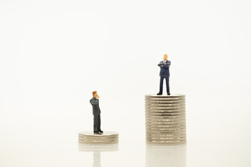 Business man miniature people figure looking and thinking for man success on top of stack of silver coin with copy space using as saving, business, and financial concept.