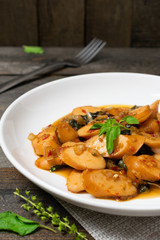 Fried basil with sausages in white dish on the old wooden table.