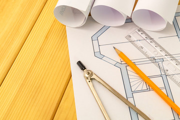 Rolled house diagrams and accessories for drawing lying on construction drawing and wooden boards
