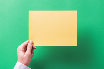 Woman's hand holding blank yellow color note paper