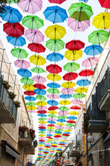 Fototapeta na wymiar sky with umbrellas. Beautiful display of colorful hanging umbrellas along a street. Umbrella Sky. Colorful umbrella roof. Natural tourist attractions Decorated with many umbrellas hanging on the walls