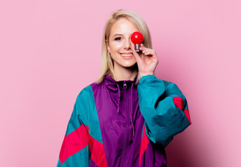 Blonde woman in 90s sport suit with bulb on pink background