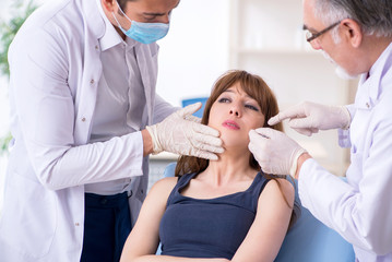 Obraz premium Two male doctors and young woman in plastic surgery concept