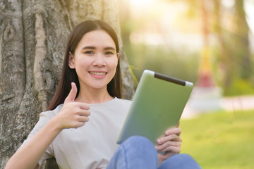 Fototapeta premium Woman use tablet sitting at city park happiness in day time online internet technology