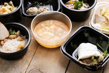 Tasty lunch in plastic containers on wooden table close up, street food delivery