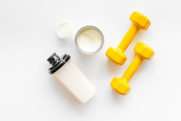 Sport nutrition. Whey protein, shaker, dumbbells on white background top-down flay lay