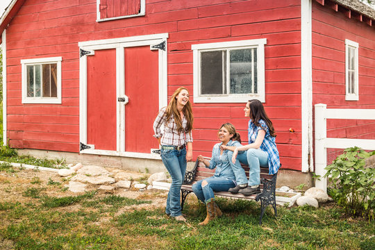Three young girls on a farm hanging out in front of a barn. Bridger, Montana, USA