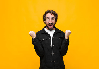 young crazy handsome man feeling shocked, excited and happy, laughing and celebrating success,...