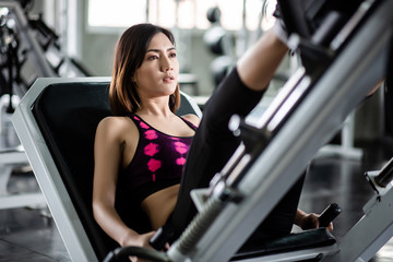 Fototapeta na wymiar Young healthy woman doing leg presses in the gym
