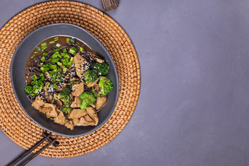 Soba noodle with teriyaki chicken and broccoli on gray stone table
