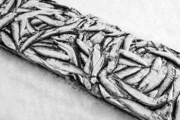 Close-up of sprat brick on the ice in fish market. Winter fishing. Frozen small silver fish...