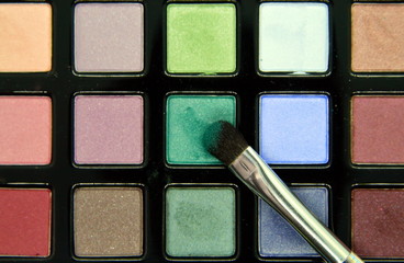 a set of eye shadow in various colors and a brush