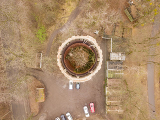 Aerial drone view. Dilapidated red brick water tower among a residential area in the forest.