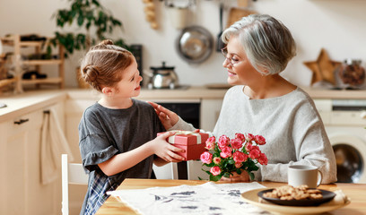 happy family. child granddaughter congratulates her grandmother and gives her flowers and a gift.