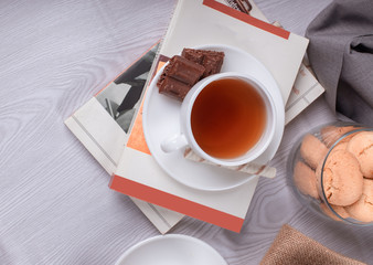 sweet snacks, cup of tea and chocolate and book on the table
