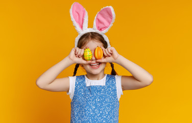 funny happy child girl with easter eggs  on yellow