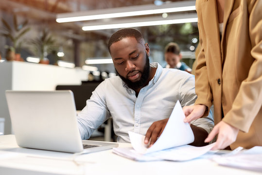 Well Done. Young Afro American Man Discussing Project Reports With His Colleague While Working Together In The Modern Office