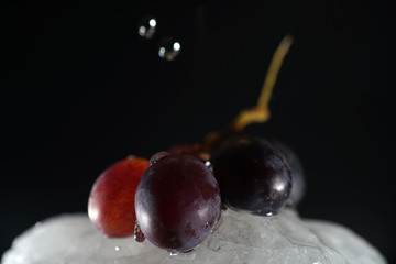 Bunches of grapes in ice water with colorful flashes photographed in studio