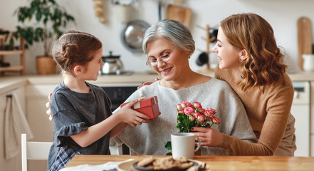 mother's day! three generations of  family mother, grandmother and daughter congratulate on the holiday, give flowers .