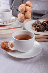 book,cup of tea and chocolate on light background