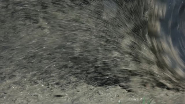 Close up spinning offroad wheel in a dirty water. Spraying dirt water, slow motion.