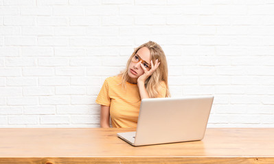 young blonde woman feeling bored, frustrated and sleepy after a tiresome, dull and tedious task,...