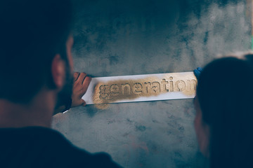 Closeup of the word GENERATION sprayed with gold on a grungy wall. 