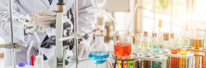 Scientist testing some blood sample at laboratory with lab glassware on the table. Science or medical research and development new antivirus concept.