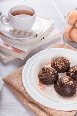 book,cup of tea and chocolate on light background