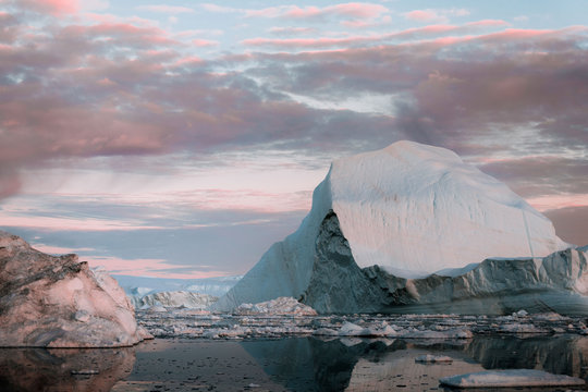 Sunset sky coloring icebergs in the arctic ocean